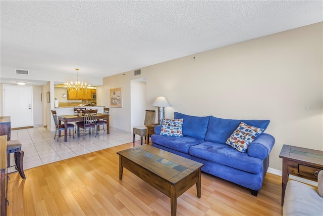 living room with light wood-style flooring, a notable chandelier, and visible vents