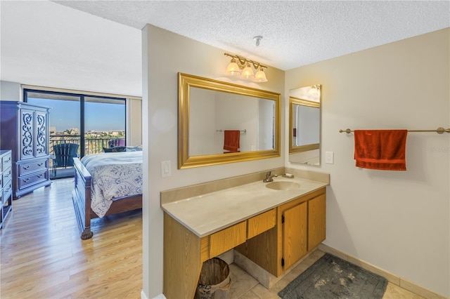 bathroom featuring vanity, a wall of windows, baseboards, a textured ceiling, and wood finished floors