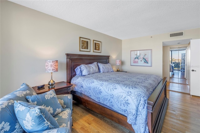 bedroom featuring visible vents, light wood-style floors, and a textured ceiling