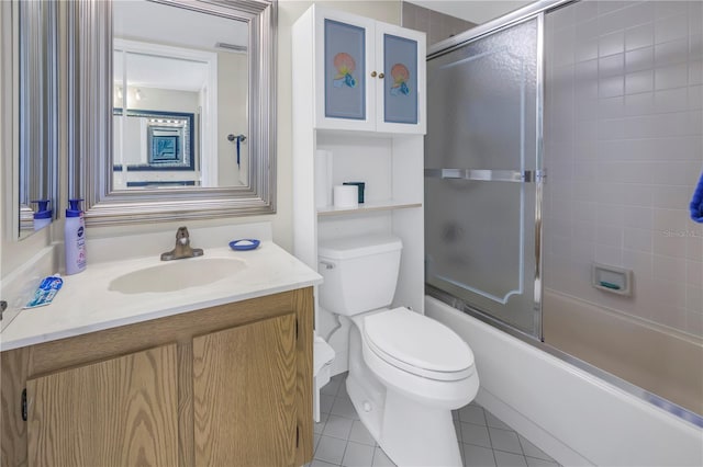 full bathroom featuring combined bath / shower with glass door, tile patterned floors, toilet, and vanity