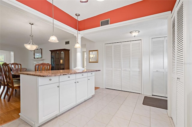 kitchen with white cabinets, light stone counters, hanging light fixtures, and a textured ceiling