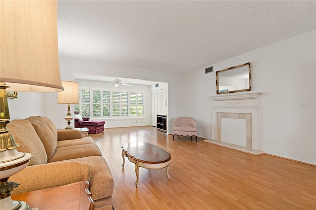 living room featuring ceiling fan, wood-type flooring, and a textured ceiling