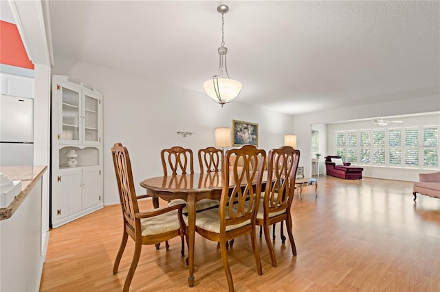 dining area with ceiling fan, a textured ceiling, and light hardwood / wood-style flooring