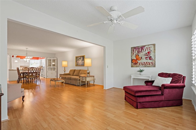 living room with hardwood / wood-style floors, ceiling fan, and a textured ceiling