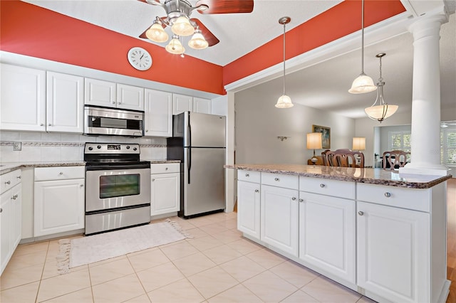 kitchen with appliances with stainless steel finishes, decorative columns, and white cabinetry