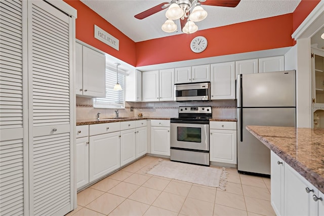 kitchen with light stone countertops, white cabinetry, stainless steel appliances, and light tile patterned floors