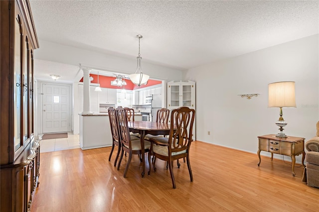 dining space with light hardwood / wood-style floors and a textured ceiling