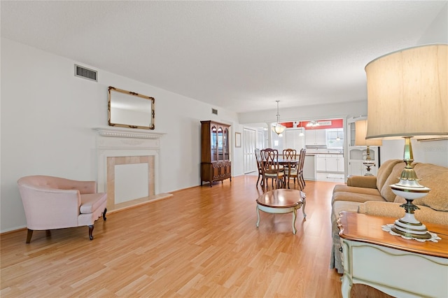 living room featuring a tiled fireplace and light hardwood / wood-style floors