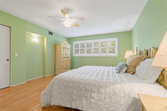 bedroom featuring ceiling fan, light hardwood / wood-style floors, and a textured ceiling