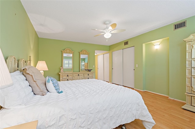 bedroom with ceiling fan, light hardwood / wood-style floors, and a textured ceiling