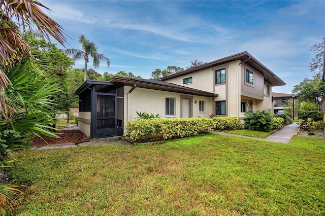 rear view of property featuring a yard and a sunroom