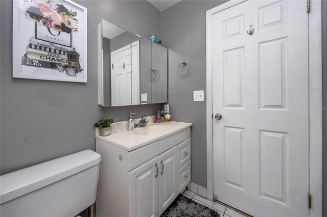 bathroom with toilet, vanity, and tile patterned floors