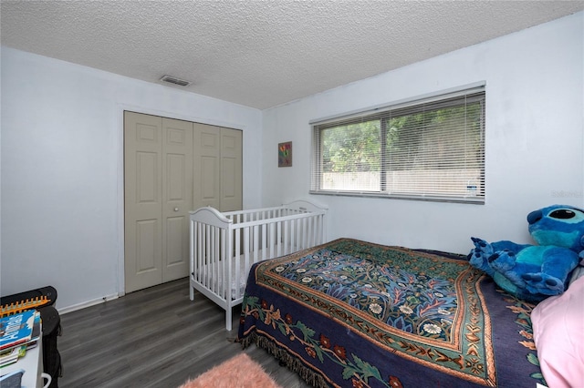 bedroom with dark hardwood / wood-style flooring, a textured ceiling, and a closet