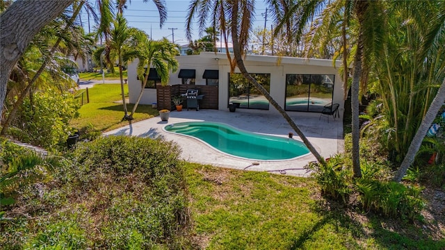 view of pool with a patio, a grill, and a lawn