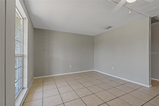 unfurnished room with light tile patterned flooring, ceiling fan, and a textured ceiling