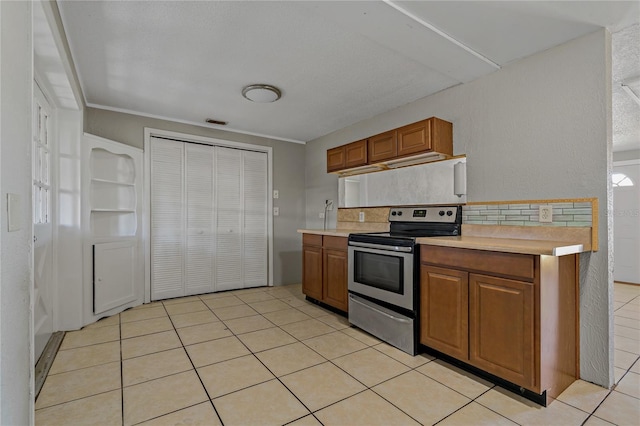 kitchen with ornamental molding, light tile patterned floors, stainless steel range with electric cooktop, and backsplash