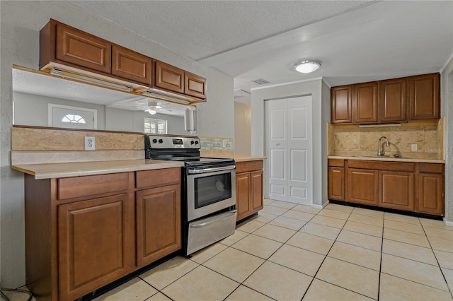 kitchen with light tile patterned flooring, sink, a textured ceiling, electric stove, and backsplash