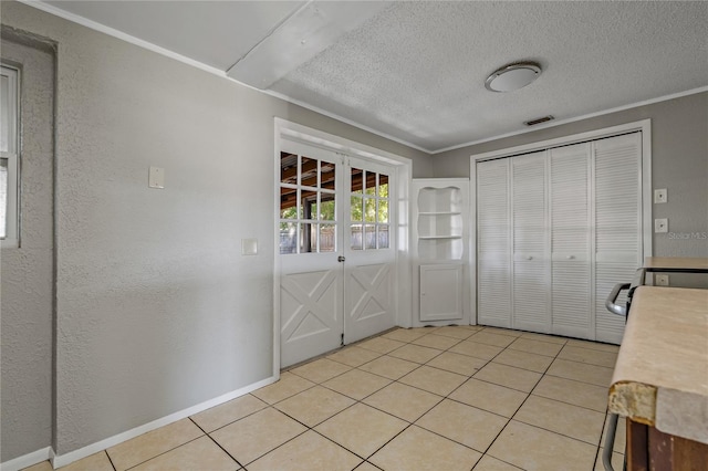 interior space with light tile patterned floors, ornamental molding, and a textured ceiling