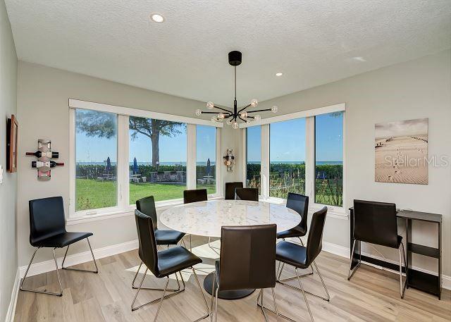 dining area with light hardwood / wood-style flooring, a textured ceiling, and a notable chandelier