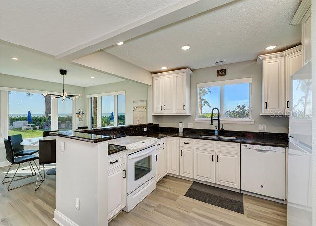 kitchen featuring white appliances, white cabinets, sink, light hardwood / wood-style flooring, and kitchen peninsula