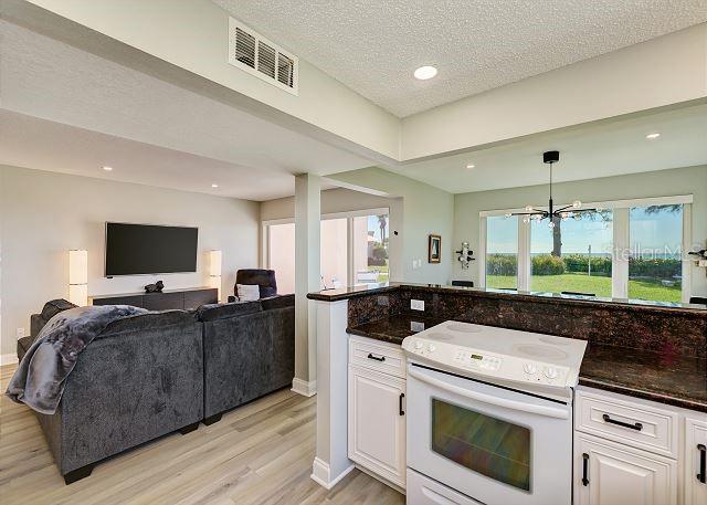 kitchen featuring white range with electric stovetop, pendant lighting, an inviting chandelier, light hardwood / wood-style flooring, and white cabinetry