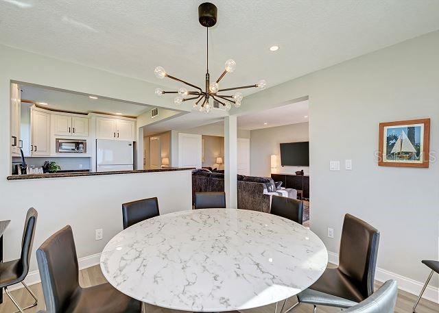 dining area with a textured ceiling, light hardwood / wood-style flooring, and a notable chandelier