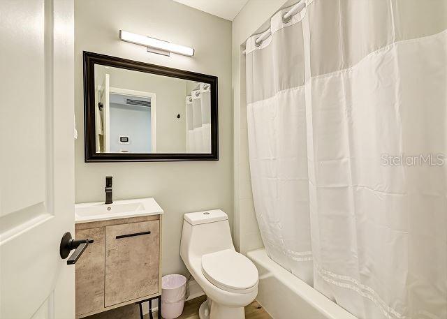 full bathroom with vanity, shower / bath combination with curtain, and toilet