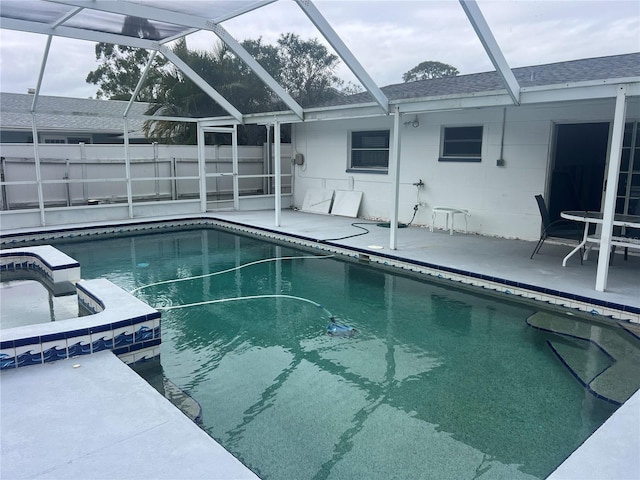 view of swimming pool with glass enclosure, a patio, and a hot tub