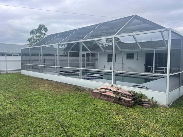 back of house with a lanai, a swimming pool with hot tub, and a yard