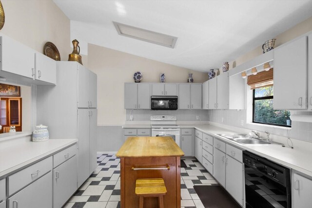 kitchen featuring lofted ceiling, black appliances, sink, a kitchen island, and white cabinetry