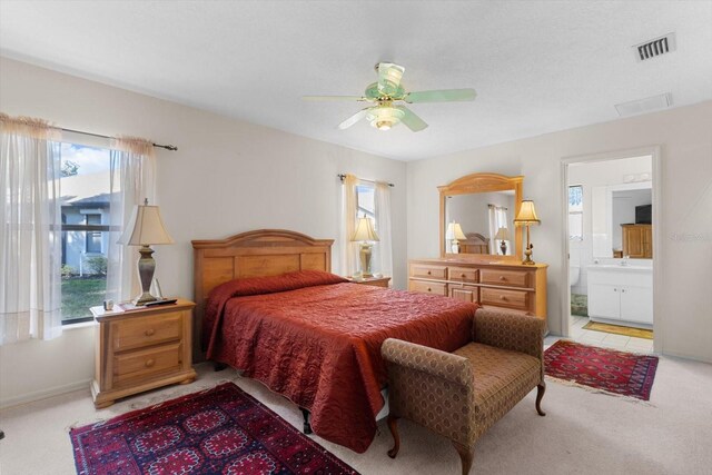 carpeted bedroom featuring connected bathroom, multiple windows, and ceiling fan