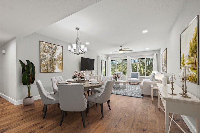 dining space with ceiling fan with notable chandelier and wood-type flooring