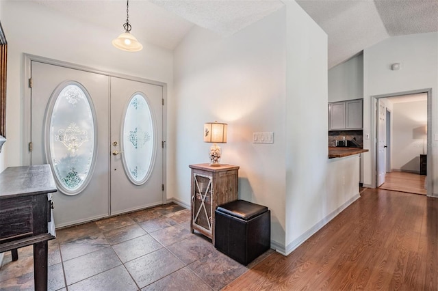 foyer featuring french doors, dark hardwood / wood-style flooring, a textured ceiling, and lofted ceiling