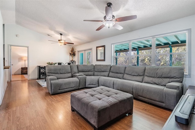 living room featuring a textured ceiling, light hardwood / wood-style flooring, ceiling fan, and lofted ceiling