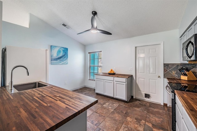 kitchen with ceiling fan, sink, stainless steel appliances, butcher block countertops, and vaulted ceiling