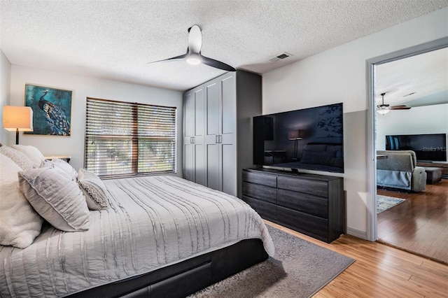 bedroom featuring ceiling fan, light hardwood / wood-style floors, a textured ceiling, and a closet