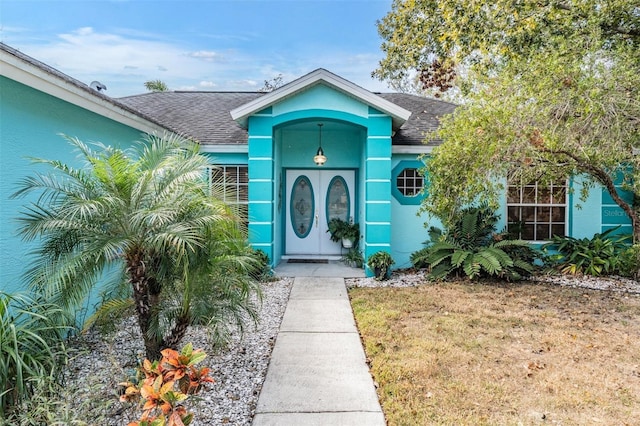 doorway to property with roof with shingles and stucco siding