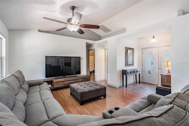 living area with visible vents, a textured ceiling, wood finished floors, and vaulted ceiling