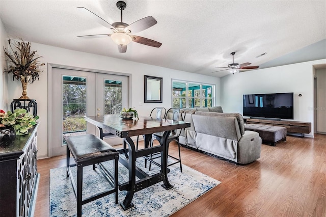 dining space with light wood-type flooring, french doors, lofted ceiling, and visible vents