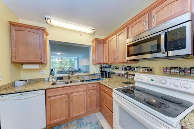 kitchen featuring light tile patterned flooring, light stone counters, white appliances, and sink