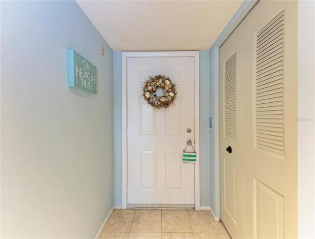 doorway featuring light tile patterned flooring and a textured ceiling