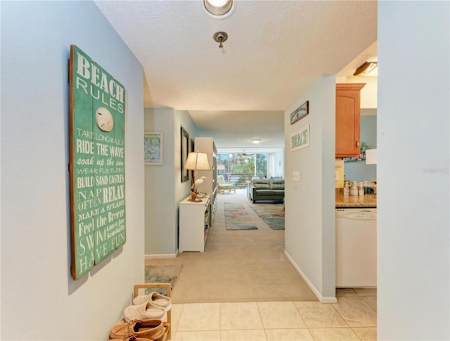 hallway with a textured ceiling and light carpet