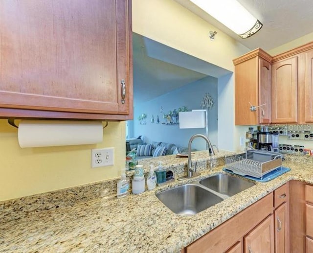 kitchen featuring light stone counters and sink