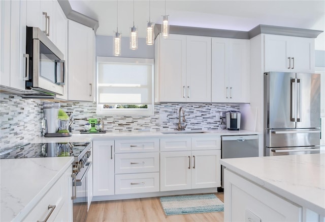 kitchen featuring sink, white cabinets, hanging light fixtures, and high end appliances