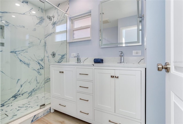 bathroom with tiled shower, hardwood / wood-style floors, and vanity