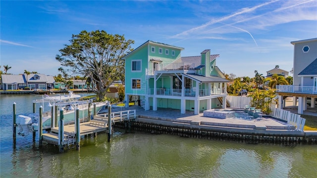 rear view of house with a patio, a water view, and a balcony