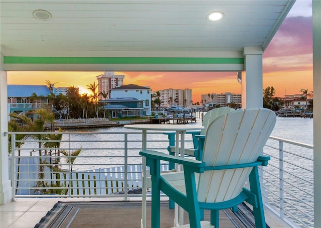 balcony at dusk featuring a water view