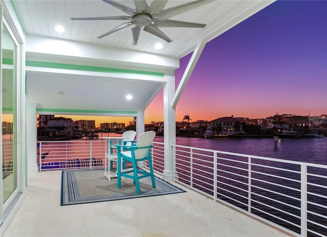 patio terrace at dusk with a water view and ceiling fan