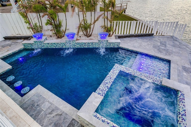 view of swimming pool with an in ground hot tub, pool water feature, and a water view