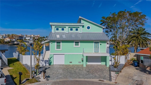 coastal inspired home with a garage, a balcony, and a water view